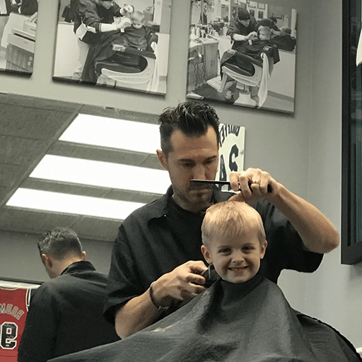 Barber cutting a young boy's hair in a salon