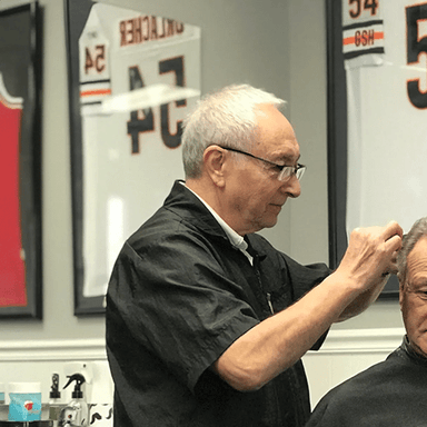 Barber styling a man's hair in a vintage barbershop.