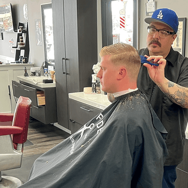 Barber cutting hair with a clipper in a barbershop